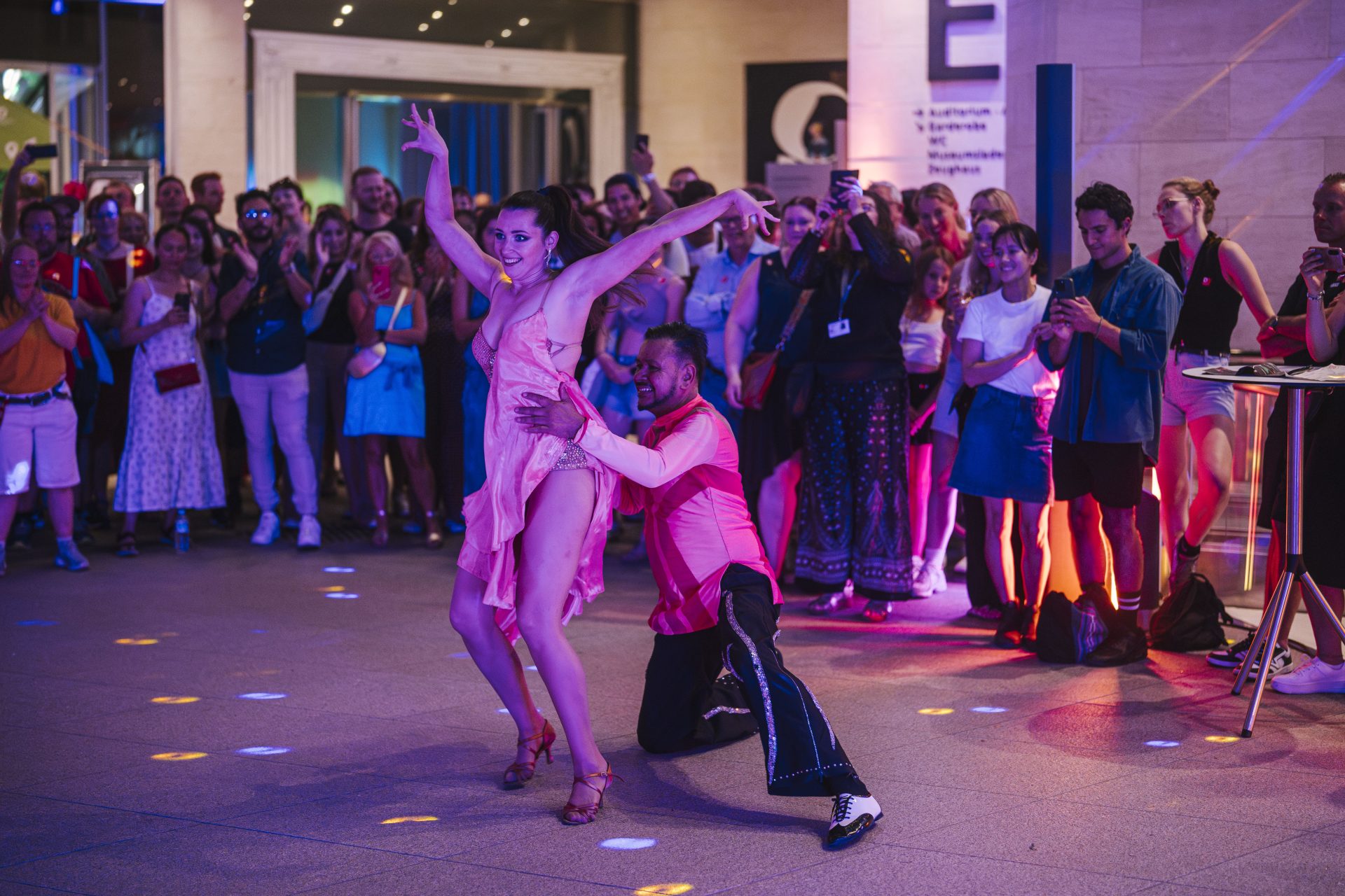 A couple dances salsa in front of numerous spectators in the foyer of the German Historical Museum