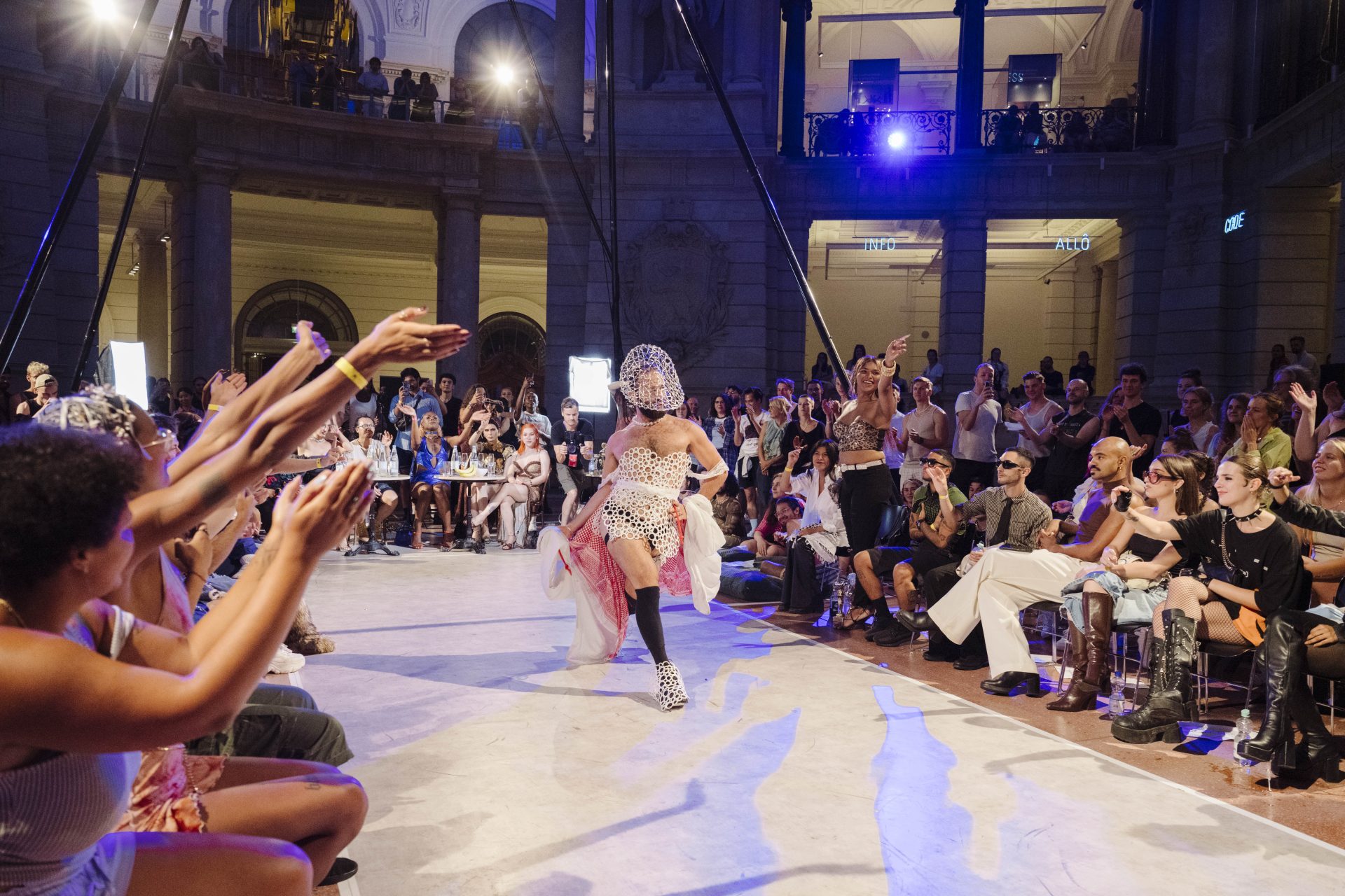 Ein*e Tänzer*in performt beim Voguing Ball im Lichthof des Museums für Kommunikation umringt von vielen Zuschauer*innen