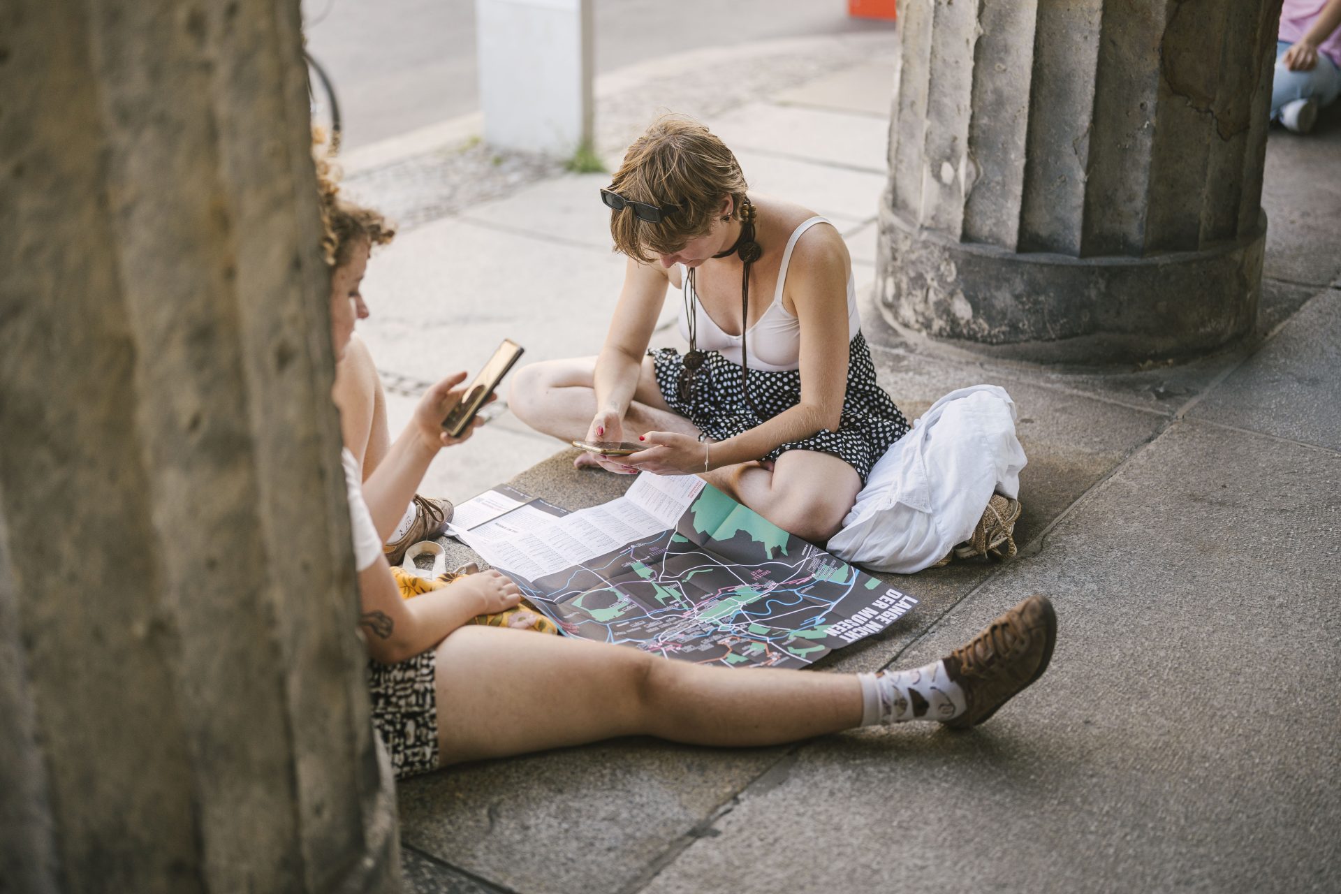 2 Besucher*innen studieren das Programm der Langen Nacht der Museen am Smartphone und mit Hilfe des Serviceplans