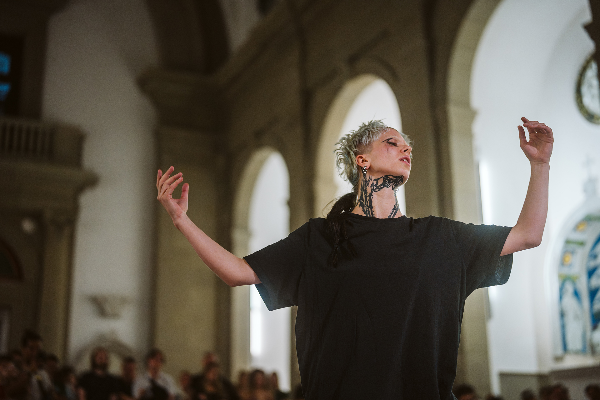 Dancer with striking tattoos in a historic room, striking an expressive pose.