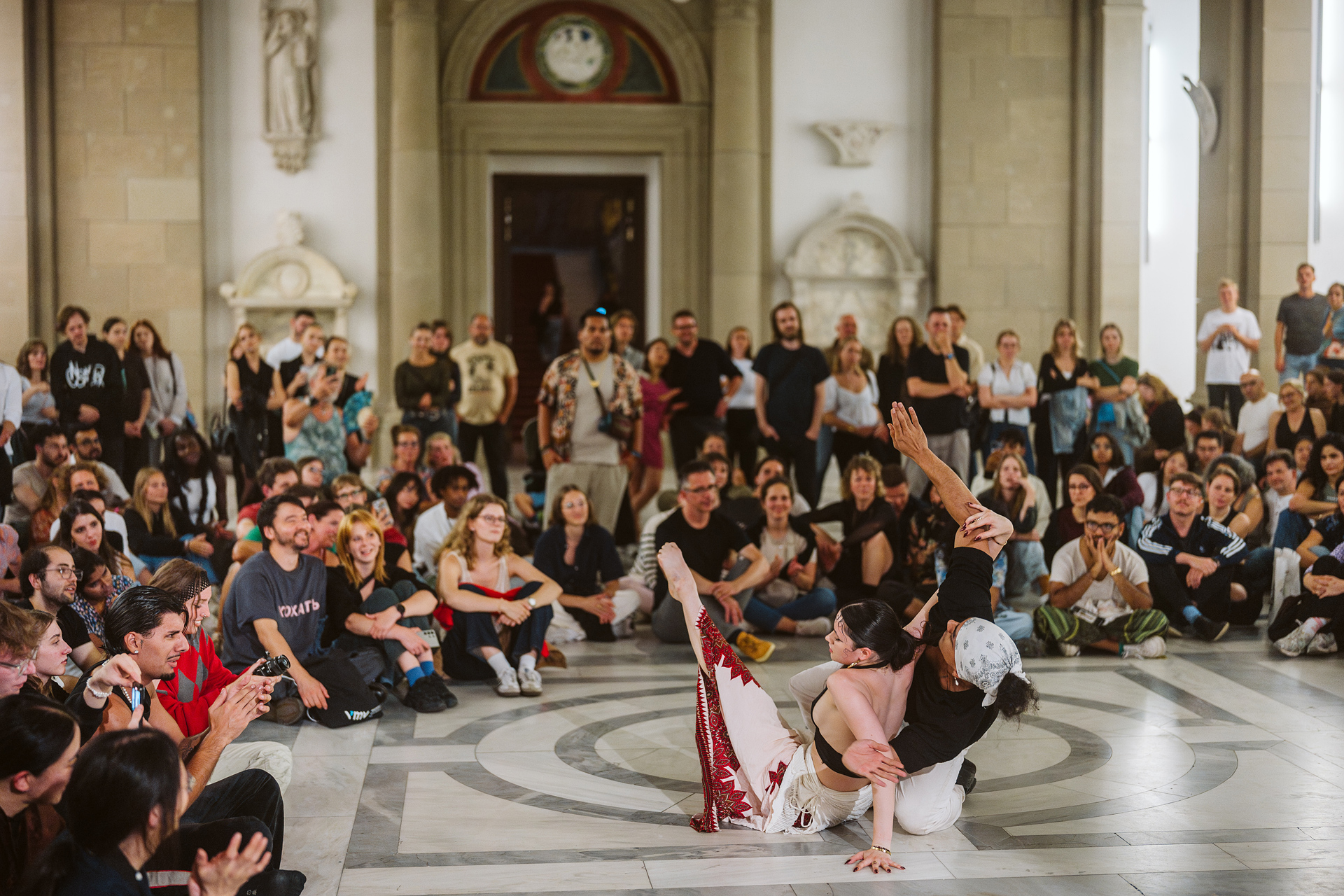 Dance performance in a bustling hall, surrounded by an attentive audience.